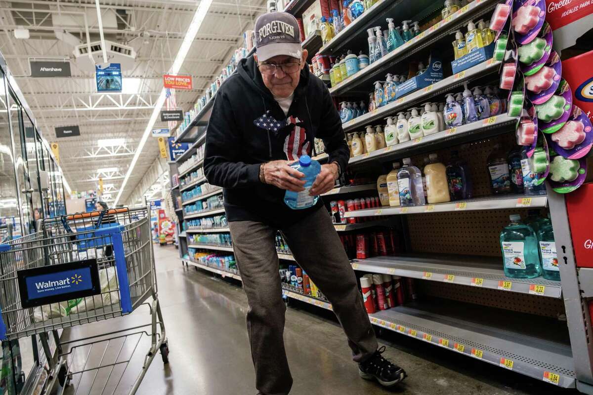 Dale Brown searches for hand sanitizer on empty shelves at Walmart in Fairfield, Calif., in February.