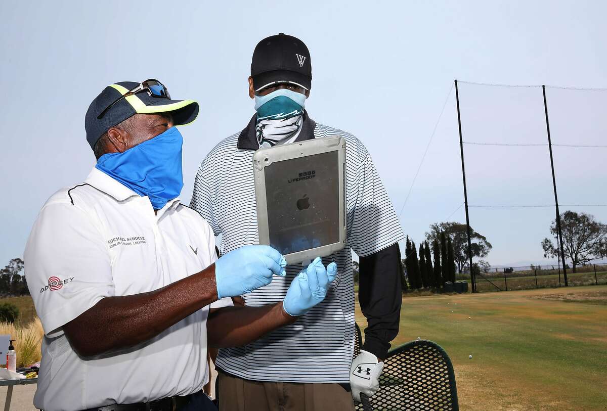 Winslow "Woody" Woodard, 68, left, shows an image of student Chad Burr's golf swing to him during a golf lesson at Corica Park Golf Course on Saturday, August 1, 2020, in Alameda, Calif. Woodard is a longtime instructor at Corica Park, where he has been giving lessons for 40 years.