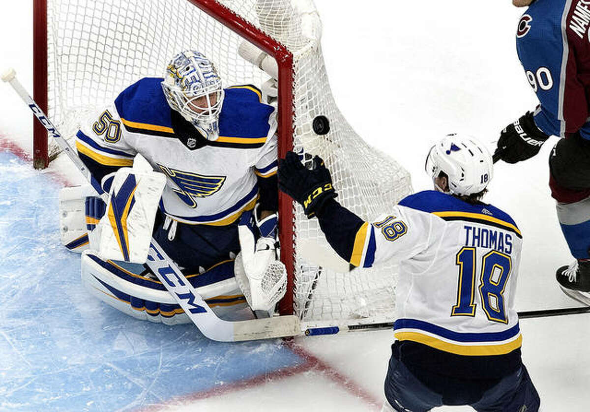 Blues goalie Jordan Binnington (50) makes a save as Robert Thomas (18) reaches for the rebound during the first period against the Colorado Avalanche in round-robin NHL hockey playoff game Sunday in Edmonton, Alberta.