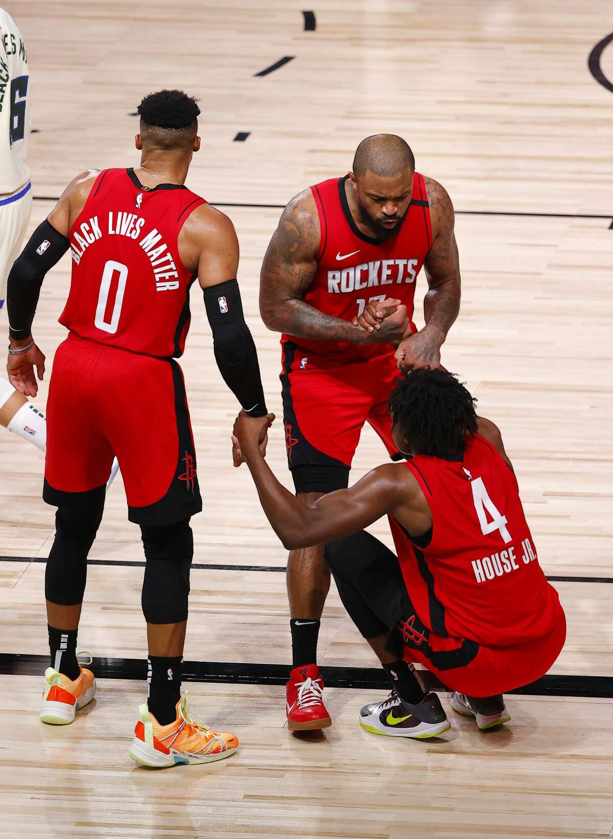 Houston Rockets' Danuel House Jr. (4) is helped up by teammates Russell Westbrook, left, and P.J. Tucker during the team's NBA basketball game against the Milwaukee Bucks on Sunday, Aug. 2, 2020, in Lake Buena Vista, Fla. (Mike Ehrmann/Pool Photo via AP)