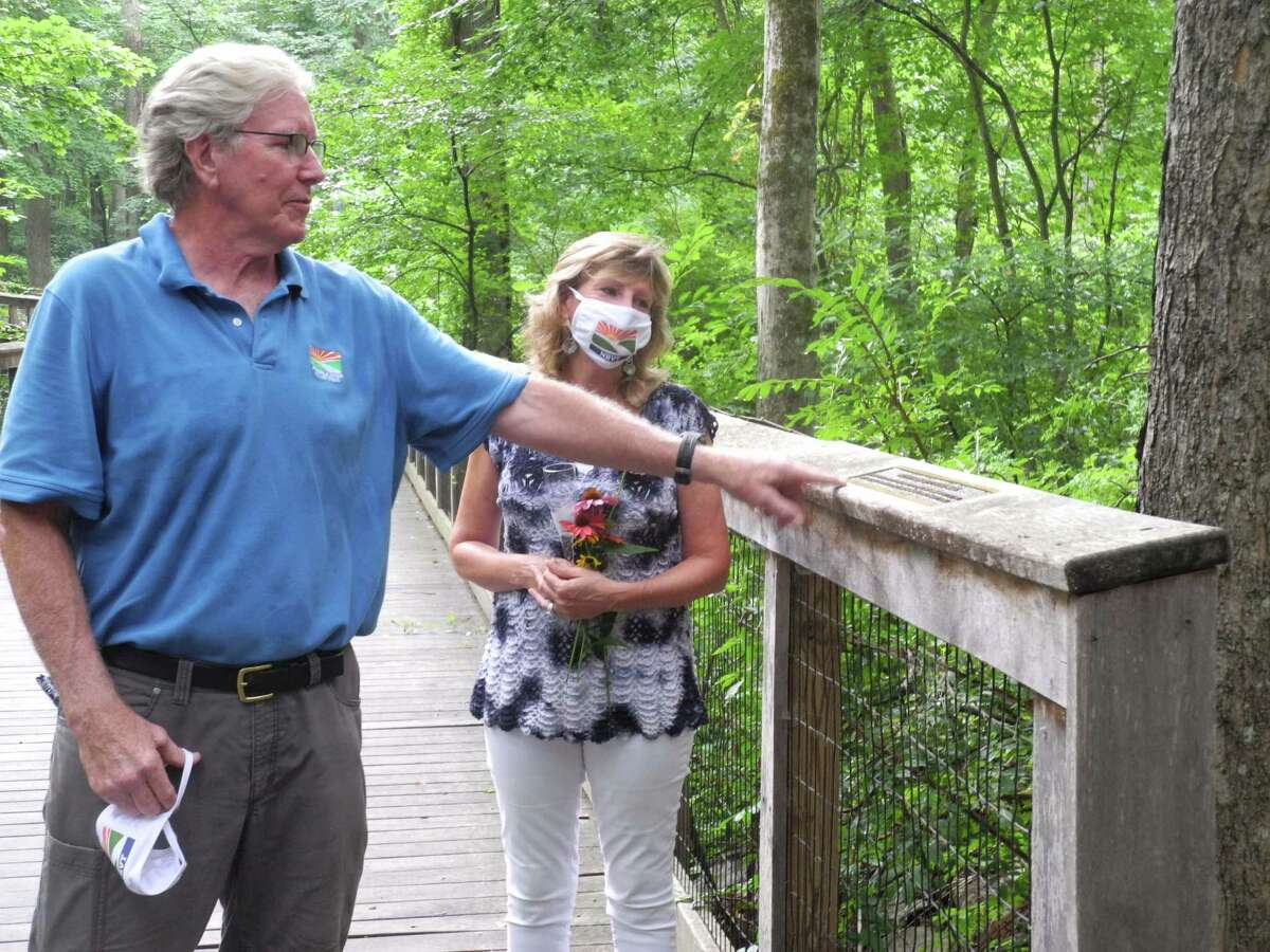 Norwalk River Valley Trail president Charlie Taney points to the plaque dedicated for the Patricia Sesto Boardwalk on July 30, 2020 in Wilton, CT. Sesto, right, has spearheaded the trail's progress for more than a decade.