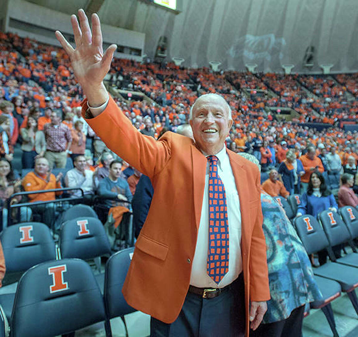 In this Dec. 2, 2015 photo, former University of Illinois basketball coach Lou Henson acknowledges the crowd while taking his seat courtside during the dedication of the court in his name at the State Farm Center in Champaign. Henson, the basketball coach who led Illinois back into the national spotlight, died July 25 at age 88.