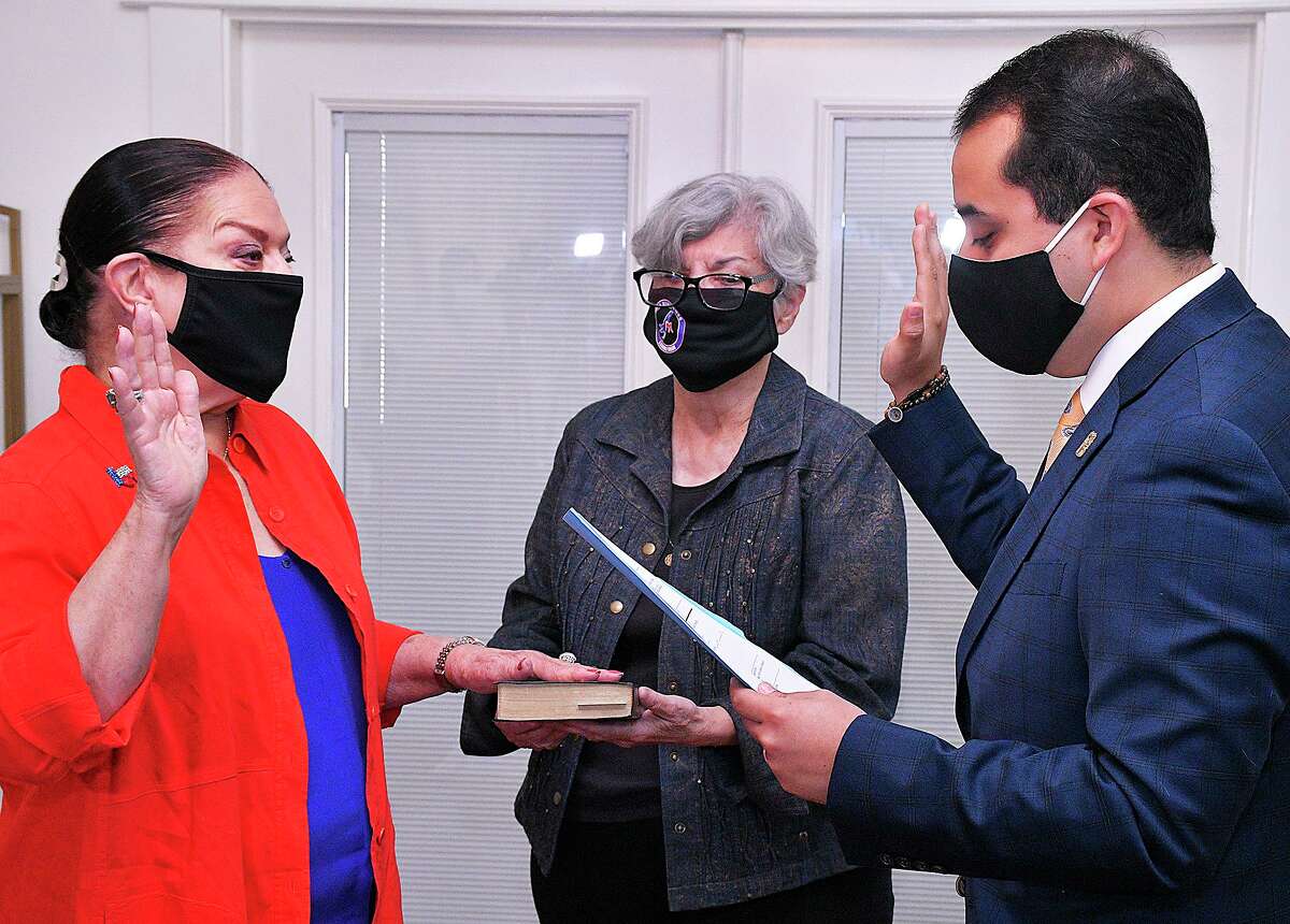 Webb County Democratic Party Secretary Ana Saenz, center, holds The Bible as Sylvia Bruni is sworn-in as the party chair by outgoing chair Albert Torres on Monday, Aug. 3.