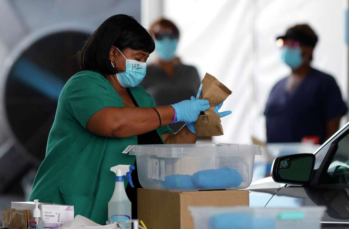A woman gathers testing supplies for a patient to use a self-administered coronavirus test at Pridgeon Stadium, one of Harris County Public Health's eight coronavirus testing sites, Friday, July 31, 2020, in Cypress.