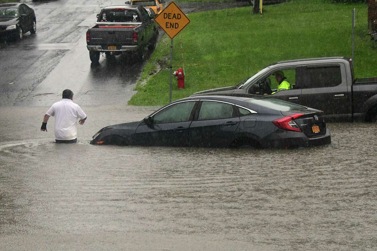 A driver evacuates his car after trying to drive through a flooded part of Hacket Blvd. near Crown Terr. and getting stuck on Tuesday, Aug. 4, 2020 in Albany, N.Y. Heavy rains due to Tropical Storm Isaias brought flooding to the area.