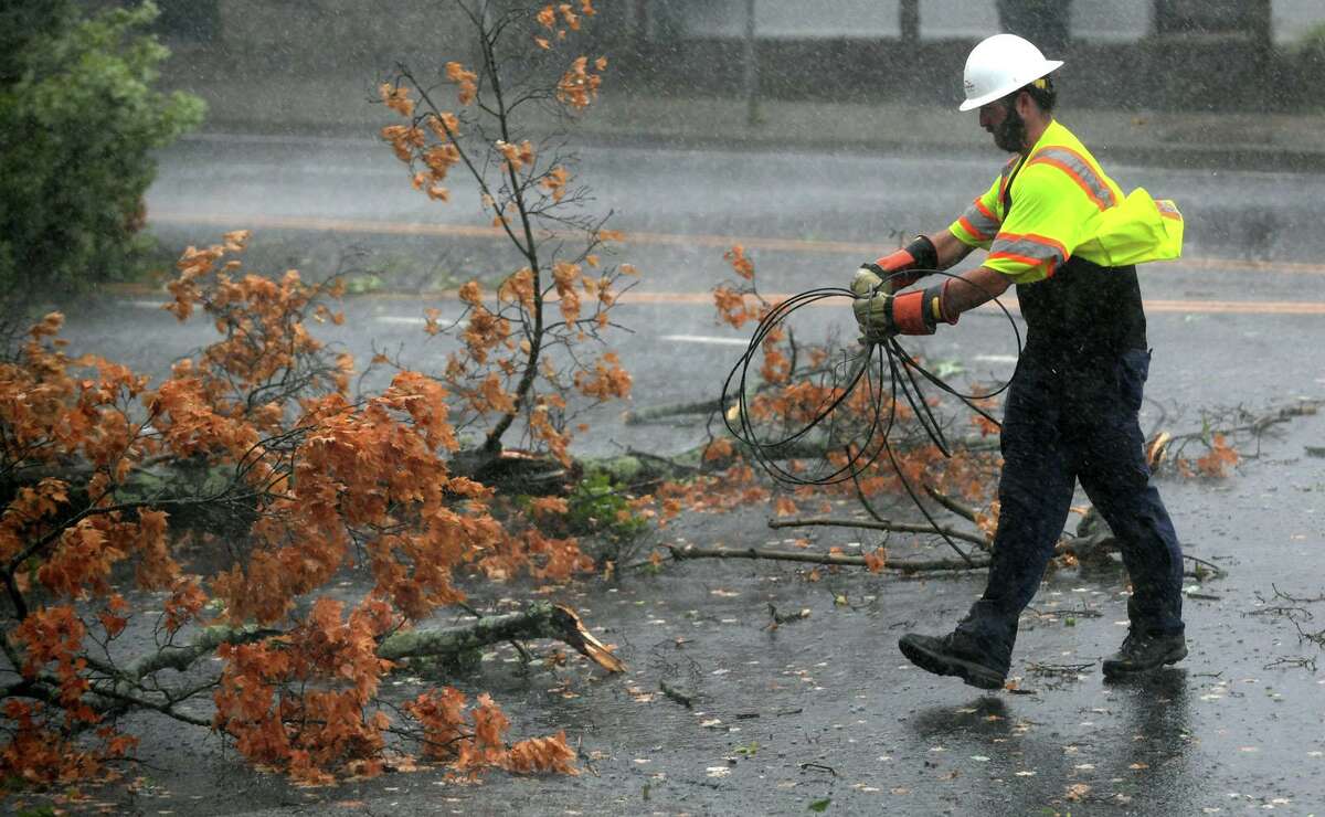 A utility worker clears wires as a fallen tree limb blocks a portion of Main Avenue in Norwalk during Tuesday’s tropical storm.