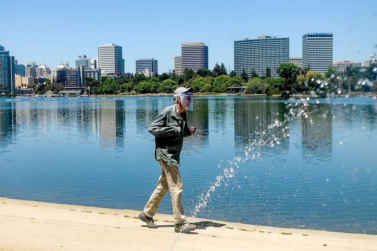 A jogger wears a face shield while exercising at Lake Merritt on Tuesday, May 26, 2020, in Oakland, Calif.