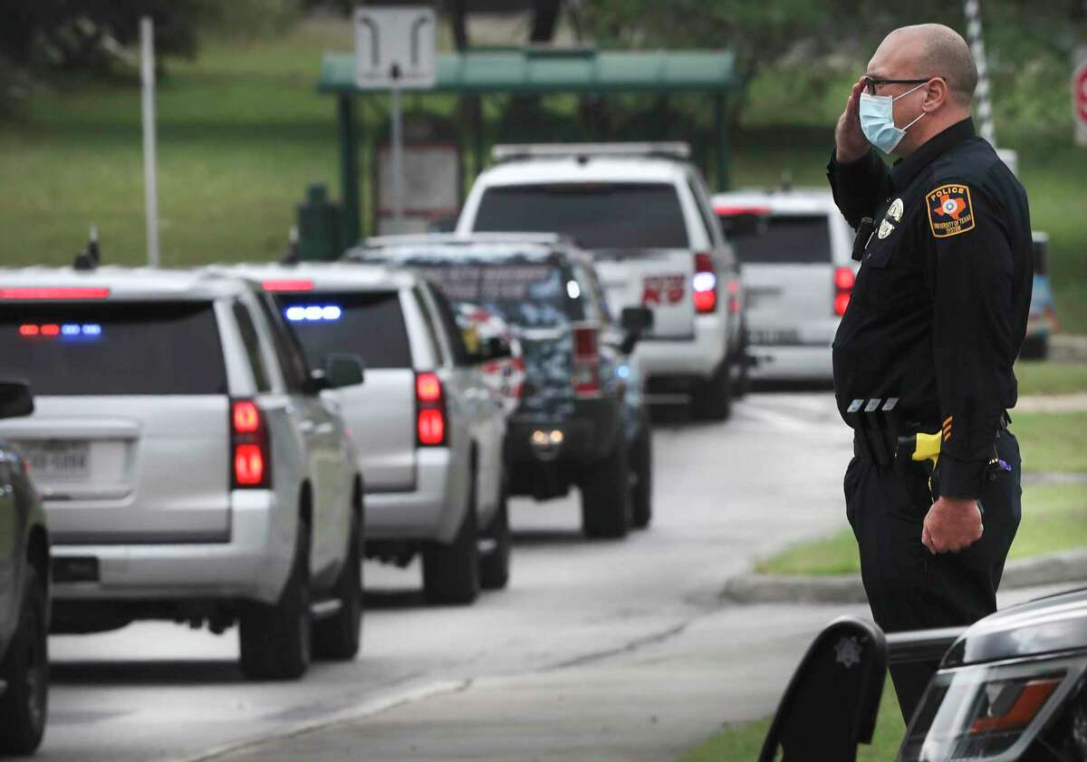 An officer from the University of Texas System Police salutes the funeral procession for Bexar County Sheriff’s Deputy Timothy De La Fuente on May 4. De La Fuente was the first employee at the Bexar County jail to die with novel coronavirus. The death toll in Bexar County now stands at 380.