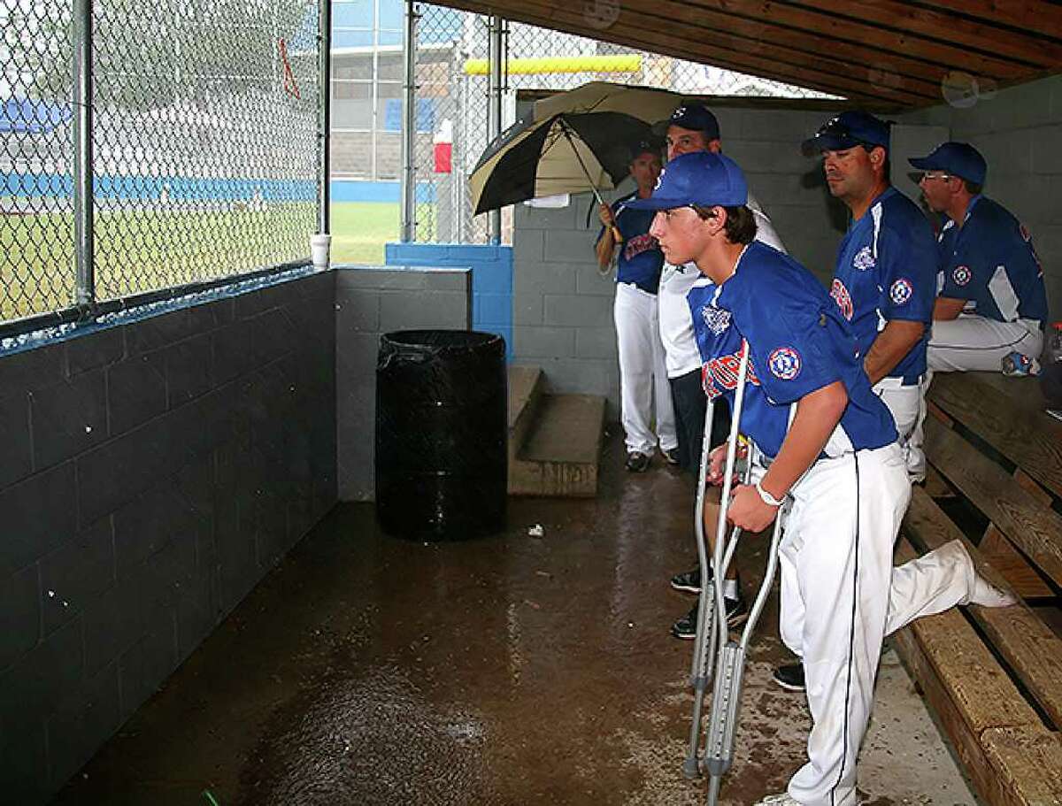 Stamford player Kyle Divico and the Stamford coaches watch from the dugout as rain falls on Burlington Field at the Babe Ruth World Series in Monticello, Arkansas on Sunday August 22, 2010. The game went into a rain delay.