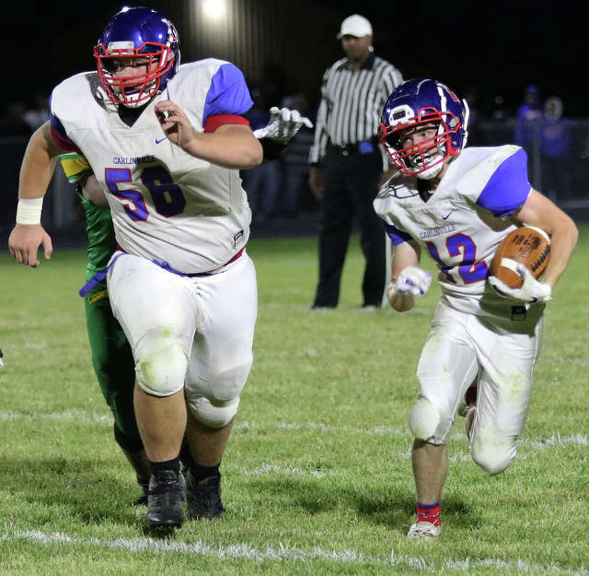 Carlinville offensive lineman Ethan Trimm (left) leads the way for running back Joe Lewis for a 38-yard run during a South Central Conference football game against Southwestern last season at Knapp Field in Piasa.