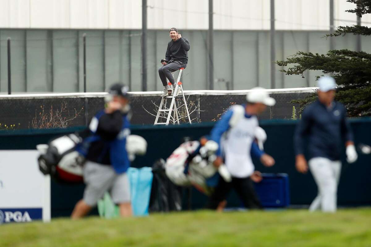 A fan watches from outside TPC Harding Park as Brooks Koepka leaves the tee box on the 13th hole during 1st round of PGA Championship in San Francisco, Calif., on Thursday, August 6, 2020.