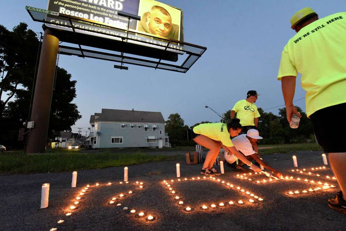 People attend a candlelight vigil at the intersection of State Street and Brandywine Avenue to draw attention to the unsolved 2019 shooting death of Roscoe Foster on Thursday, Aug. 6, 2020 in Schenectady, N.Y. A reward billboard is seen in the background. (Lori Van Buren/Times Union)