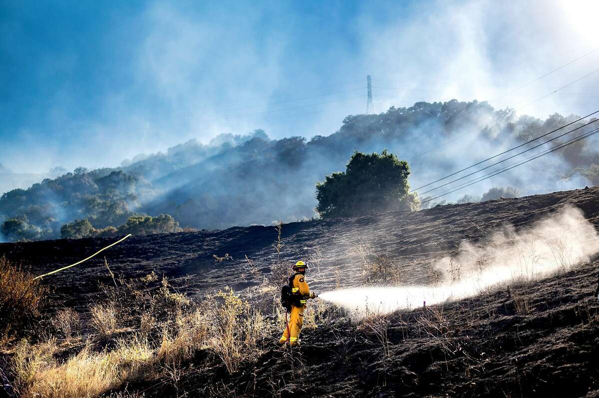 A firefighter sprays water while mopping up after the Calaveras Fire on Thursday, Aug. 6, 2020, near Sunol, Calif. Firefighters were investigating the incident, located at a San Francisco Public Utilities Commission facility, as a crime scene.