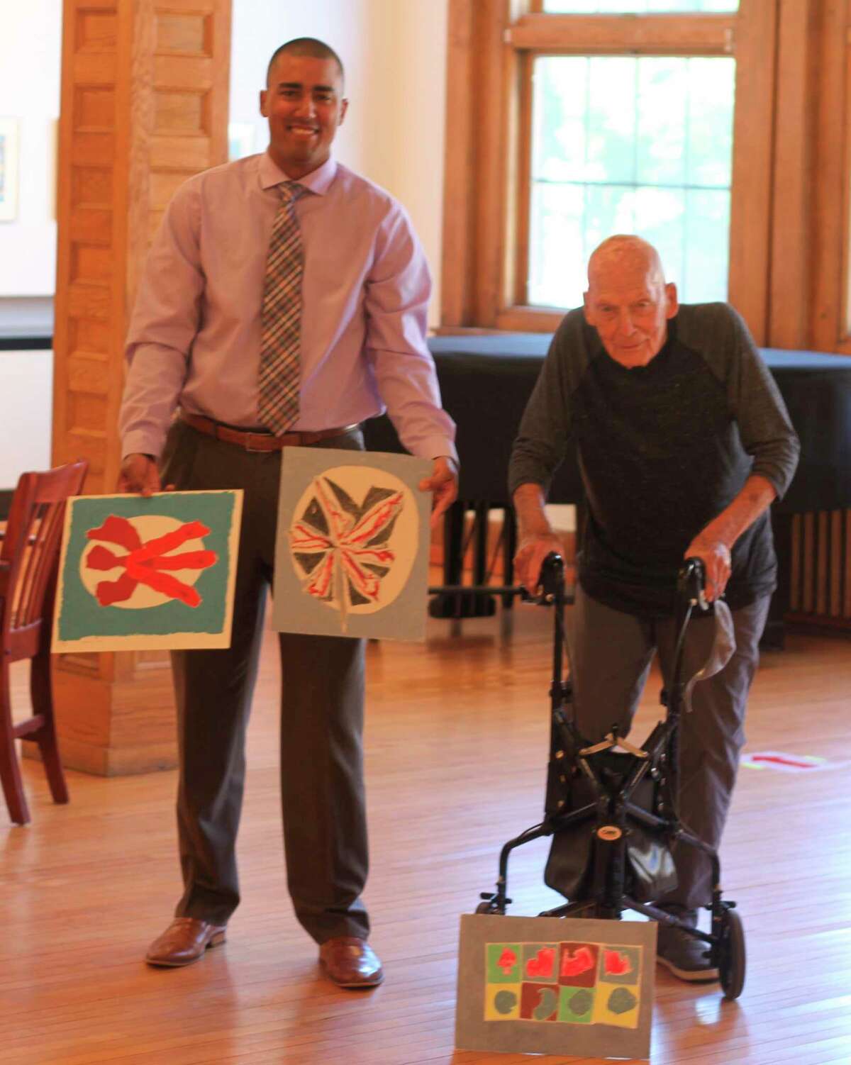 Executive director of the Ramsdell Regional Center for the Arts, Xavier Verna (left) stands with Manistee native and nationally renowned artist Leslie Laskey and three paintings Laskey donated to the RRCA in August 2020. (Kyle Kotecki/News Advocate)