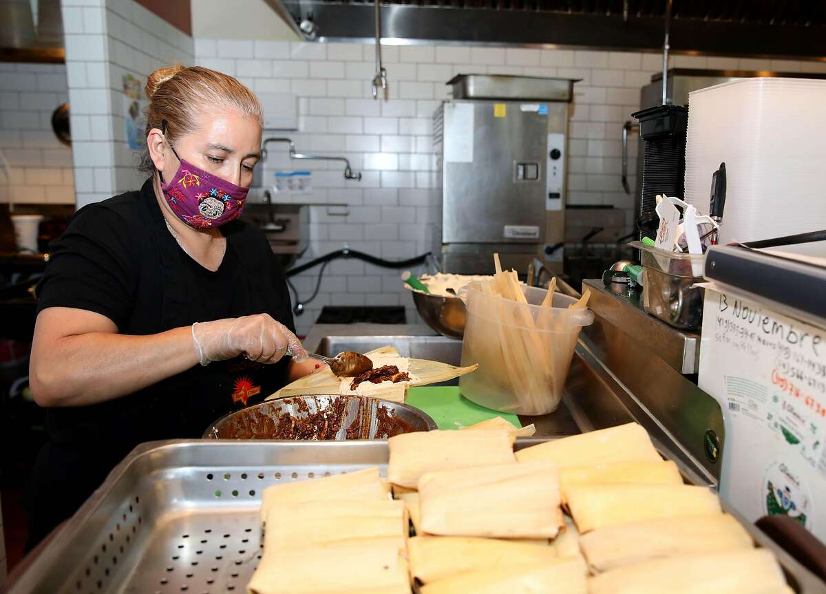 Isabel Caudillo, owner of El Buen Comer, a Latino restaurant, makes tamales in the kitchen on Friday, August 7, 2020, in San Francisco, Calif. The restaurant is located at 3435 Mission St. In California, Latino- and female-owned businesses have been hit particularly hard by the pandemic. Research from UC Santa Cruz shows that since March, more Latino-owned and female-owned businesses have closed than white- and male-owned, respectively. These businesses tend to be in the hardest-hit industries, like food service, construction, or personal care. A survey by Stanford's Graduate School of Business shows that Latino-owned businesses have less cash on hand and less access to government aid than white-owned businesses, making survival more difficult.