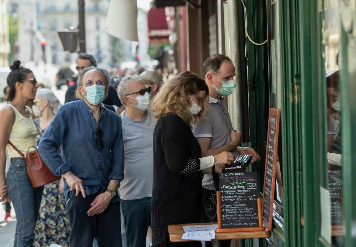People wear masks to help curb the spread of the coronavirus line up to buy an ice-cream in Paris, Thursday May 21, 2020 as France gradually lifts its Covid-19 lockdown.
