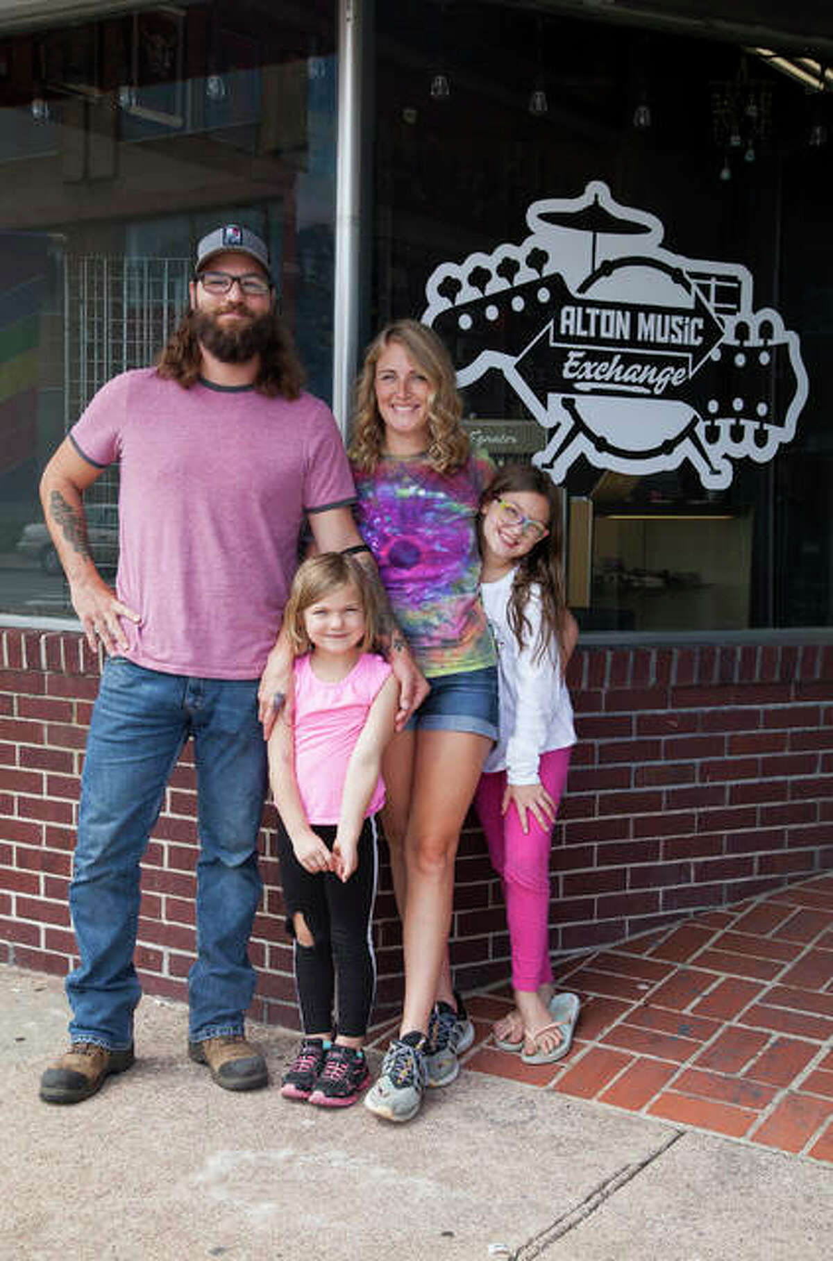 Jared and Jenny Unfried with their two daughters in front of their newly opened music store, Alton Music Exchange, 556 E. Broadway in Downtown Alton. By encouraging local musicians to bring in guitars, amps and whatever else they might have for trade or sale, the couple hopes to build a hub for local musicians and strengthen the local music community.