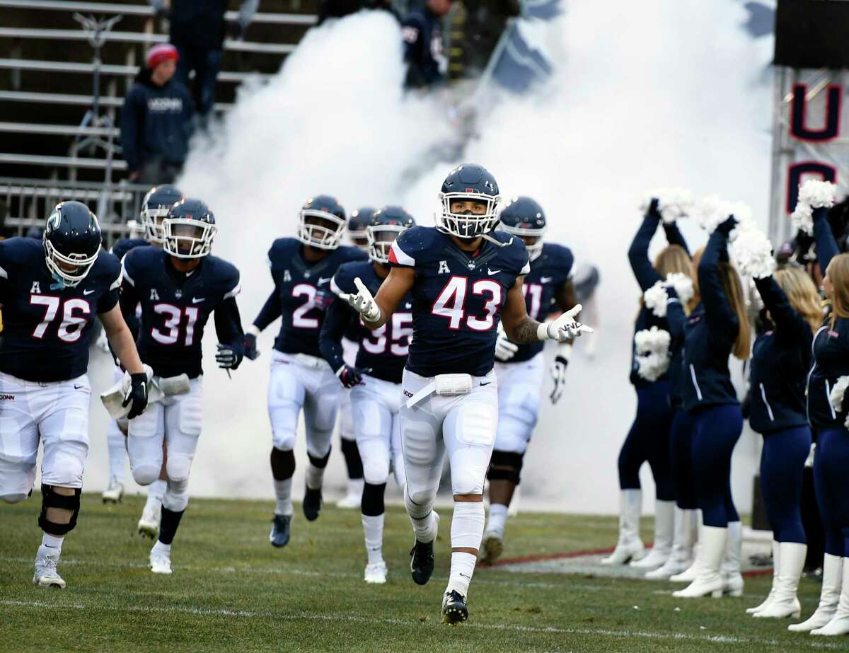 UConn players take the field before a game against Temple at Rentschler Field.