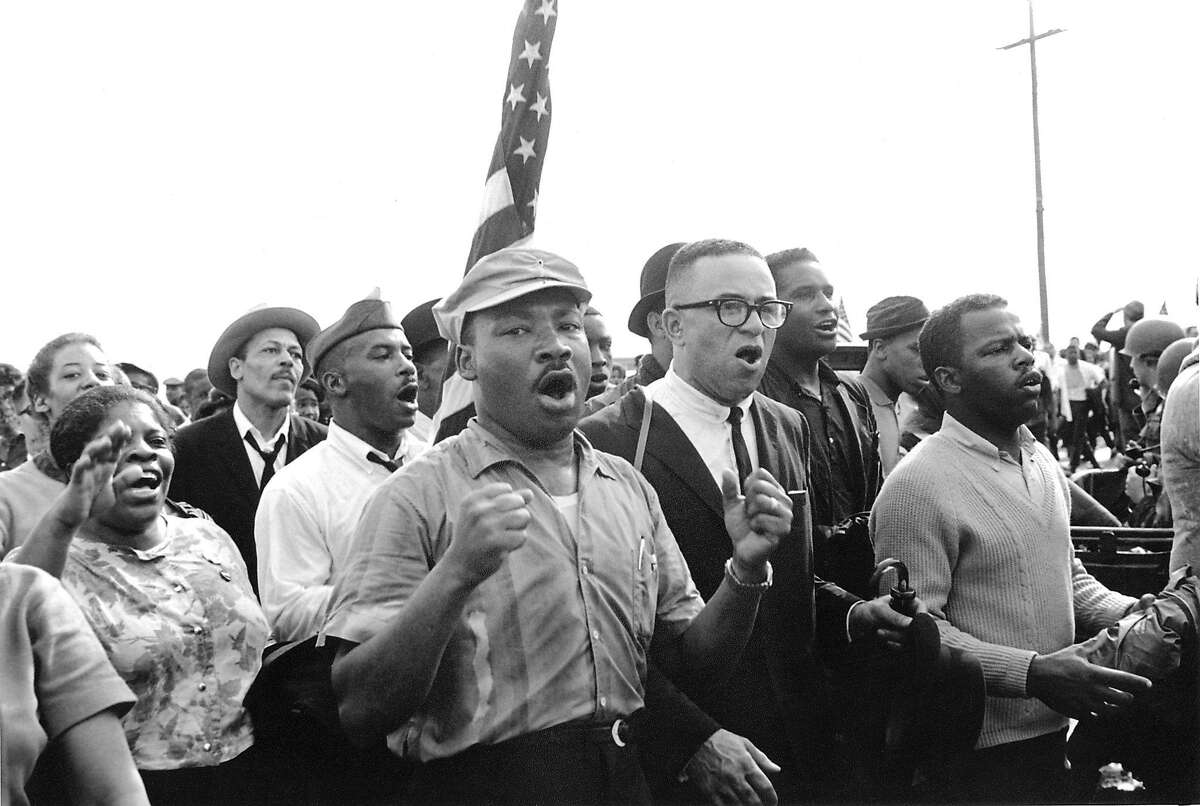 Martin Luther King leads singing marchers toward Montgomery during the Selma March, 1965. On right, SNCC Chairman, John Lewis