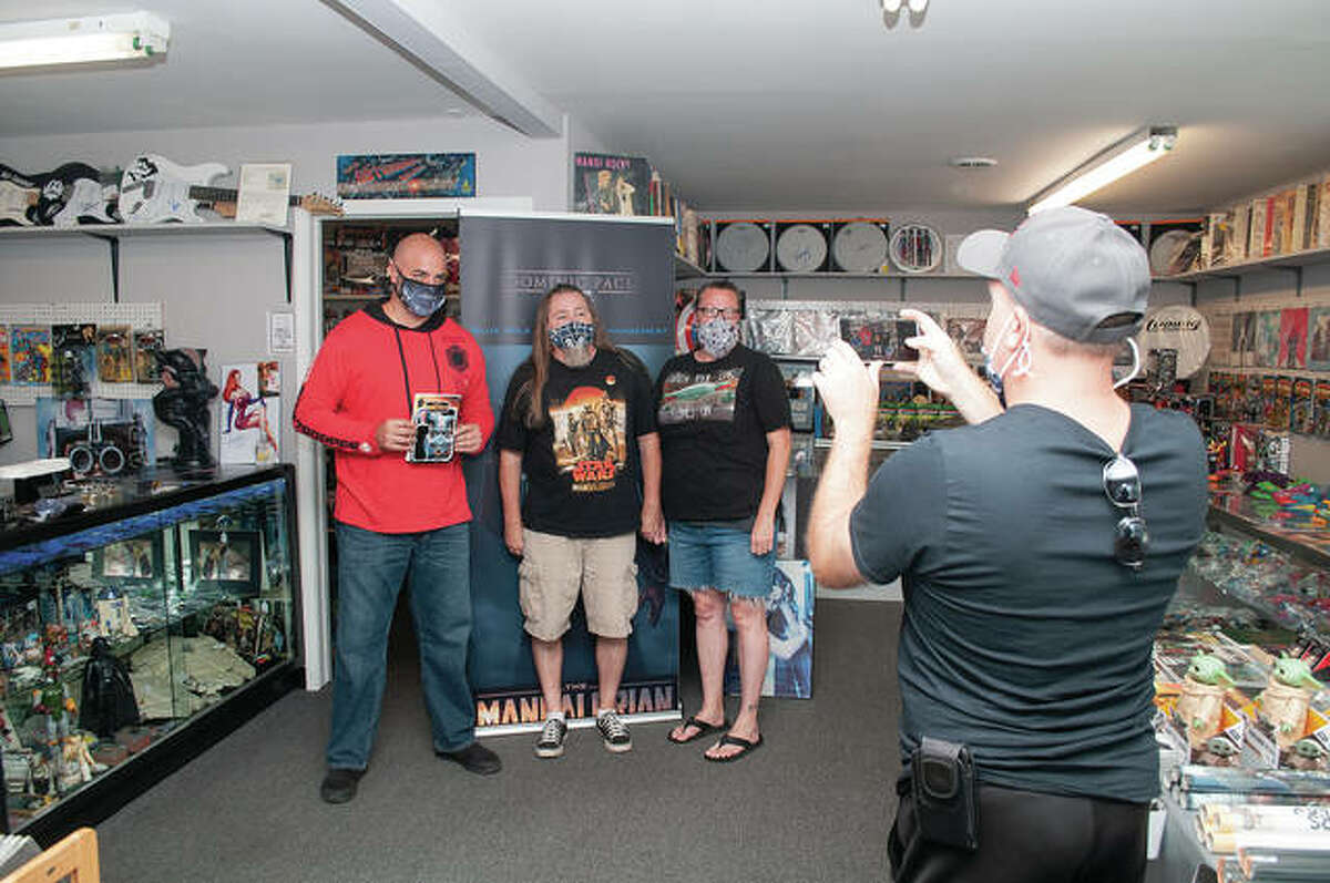 Dominic Pace (left) stands with John and Kelly Comerford on Saturday at Destination Toys in Jacksonville. Pace plays the character Gekko the Bounty Hunter on the Disney Plus “Star Wars” series “The Mandalorian.” Store owner Mark Medley (front) invited Pace to visit.