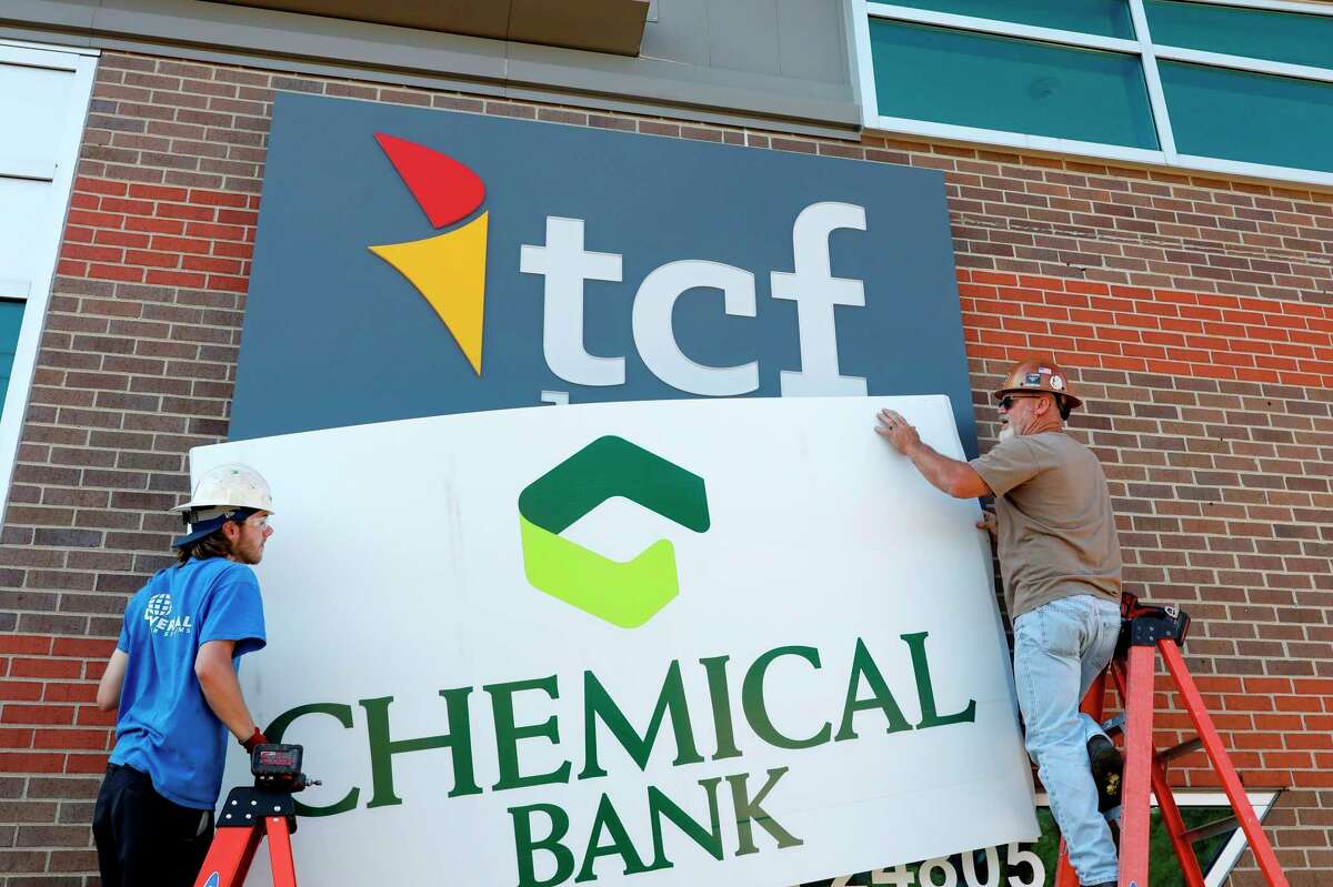 Universal Sign employees Kris Suhr and Eddie Bruining (in blue shirt) change over the Chemical Bank signs at the bank's location on 12 Mile Road in Southfield on Friday, Aug. 7. (Photo provided/TCF)