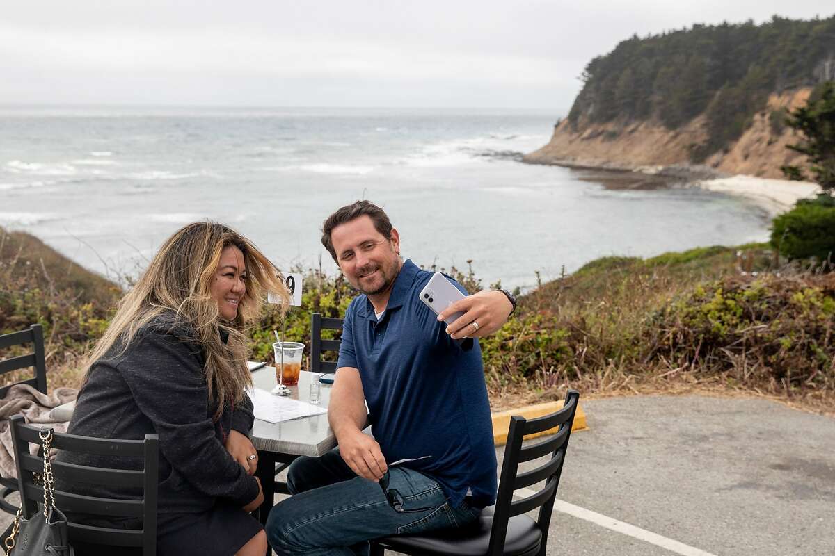 Abigail and Daniel Johnson of San Jose take a selfie after finishing their meal at Moss Beach Distillery in Moss Beach, Calif. Saturday, August 1, 2020. The restaurant has opened their standard patio overlooking the ocean to patrons and have also added extra socially distanced tables in their parking lot.