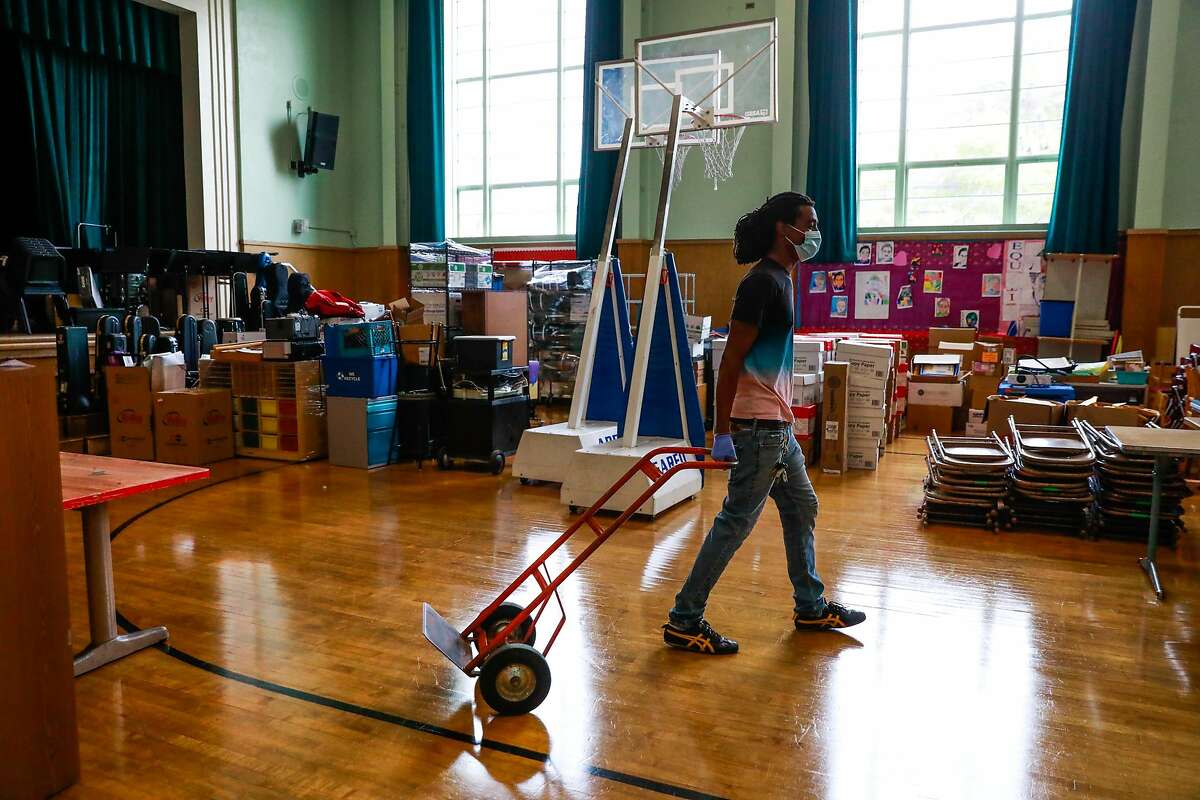 Head custodian Ashanti Lewis pulls a dolly as he works on organizing the assembly room at Sankofa Academy on the first day of school on Monday, Aug. 10, 2020 in Oakland, California.