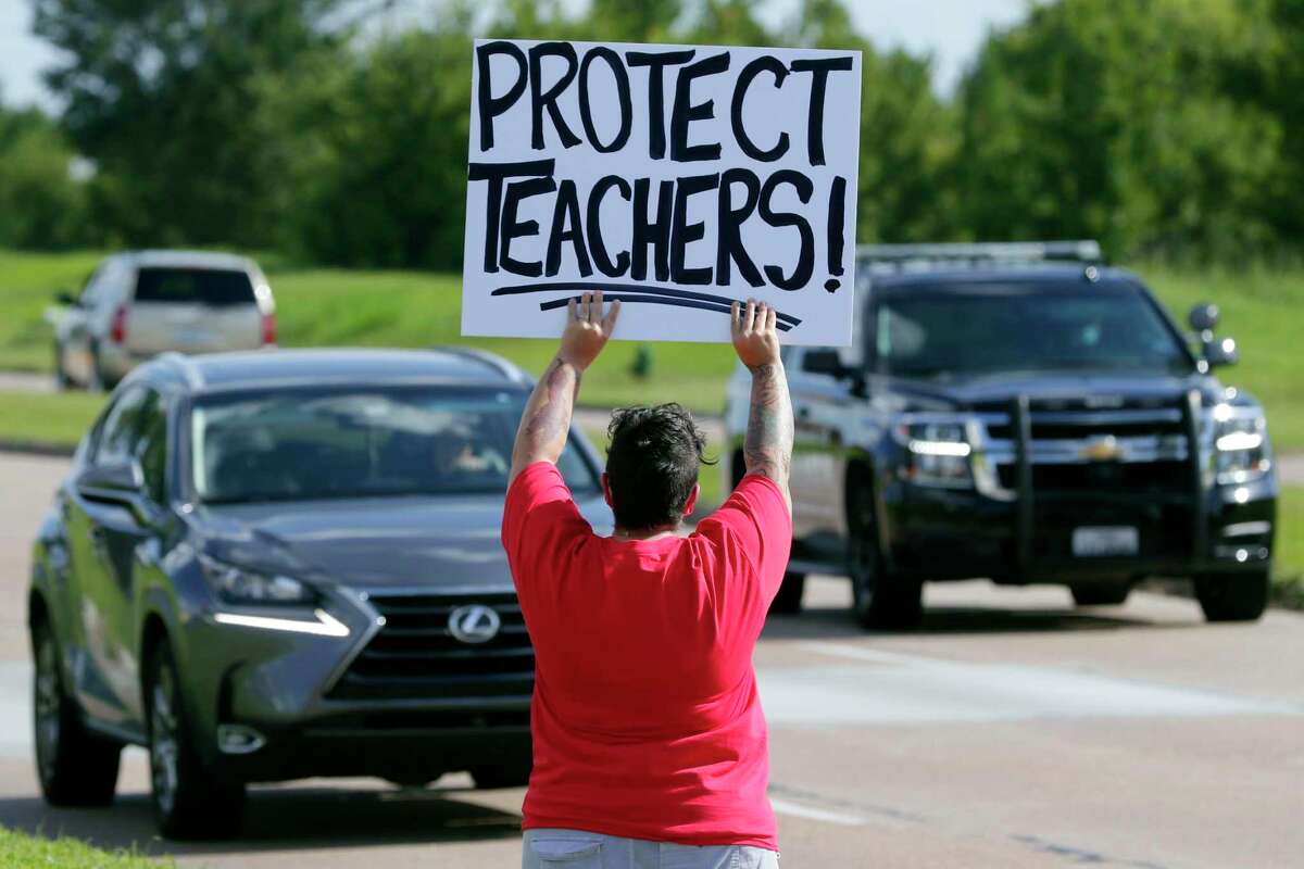 Cy-Fair teachers, staff and parents gather with protest signs at the main entrance to the district administration building against the COVID-19 teaching requirements before a Cy-Fair school board meeting Monday, Aug. 10, 2020 in Houston, TX.