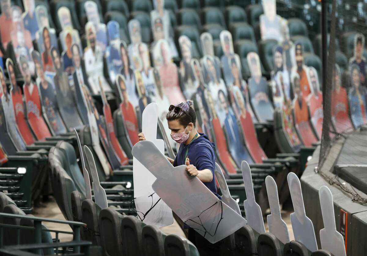 Houston Astros team photographer Alex Bierens de Haan places fan cutouts in the Diamond Club seats during batting practice before the start of an MLB baseball game at Minute Maid Park, Monday, August 10, 2020, in Houston.