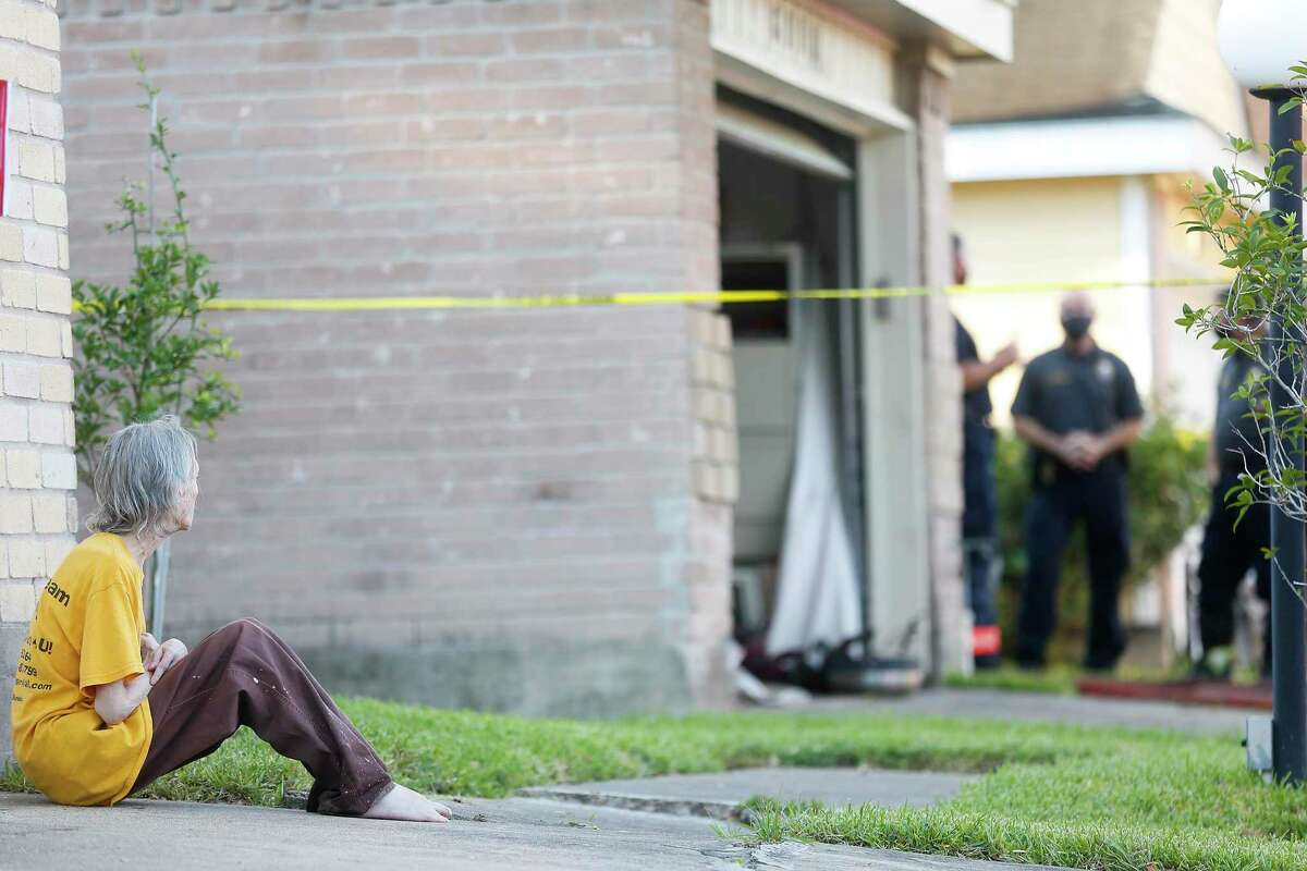 A resident watches as Houston Fire Department investigates a fatal fire in a group home for adults with special needs in Houston on Tuesday, Aug. 11, 2020.
