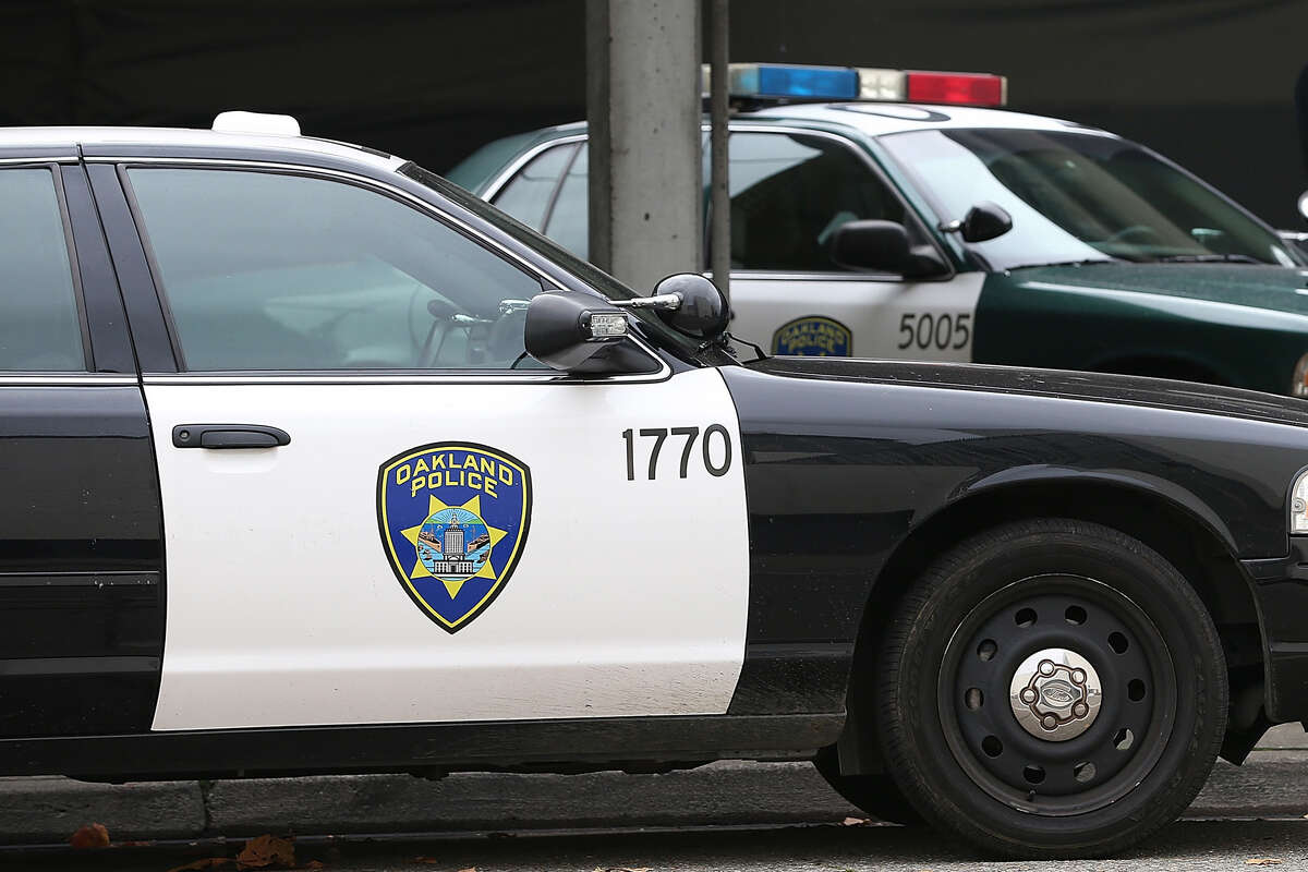 An Oakland Police officer walks by patrol cars at the Oakland Police headquarters.