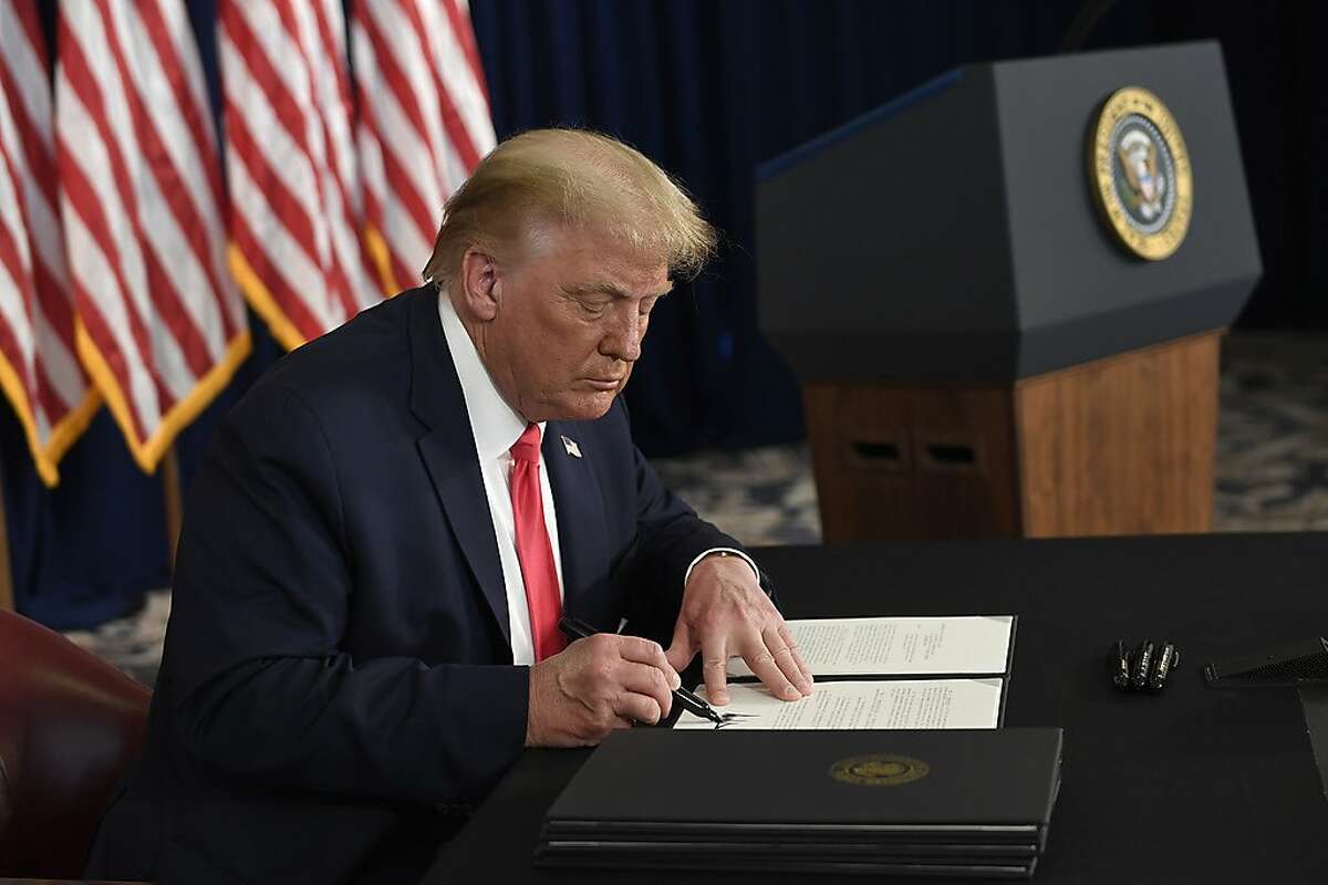 President Donald Trump signs one of four executive orders addressing the economic fallout from the COVID-19 pandemic at his Trump National Golf Club in Bedminster, N.J., Saturday, Aug. 8, 2020. Trump signed the executive orders and bypassed the nation's lawmakers as he claimed the authority to defer payroll taxes and replace an expired unemployment benefit with a lower amount after negotiations with Congress on a new coronavirus rescue package collapsed. (AP Photo/Susan Walsh)