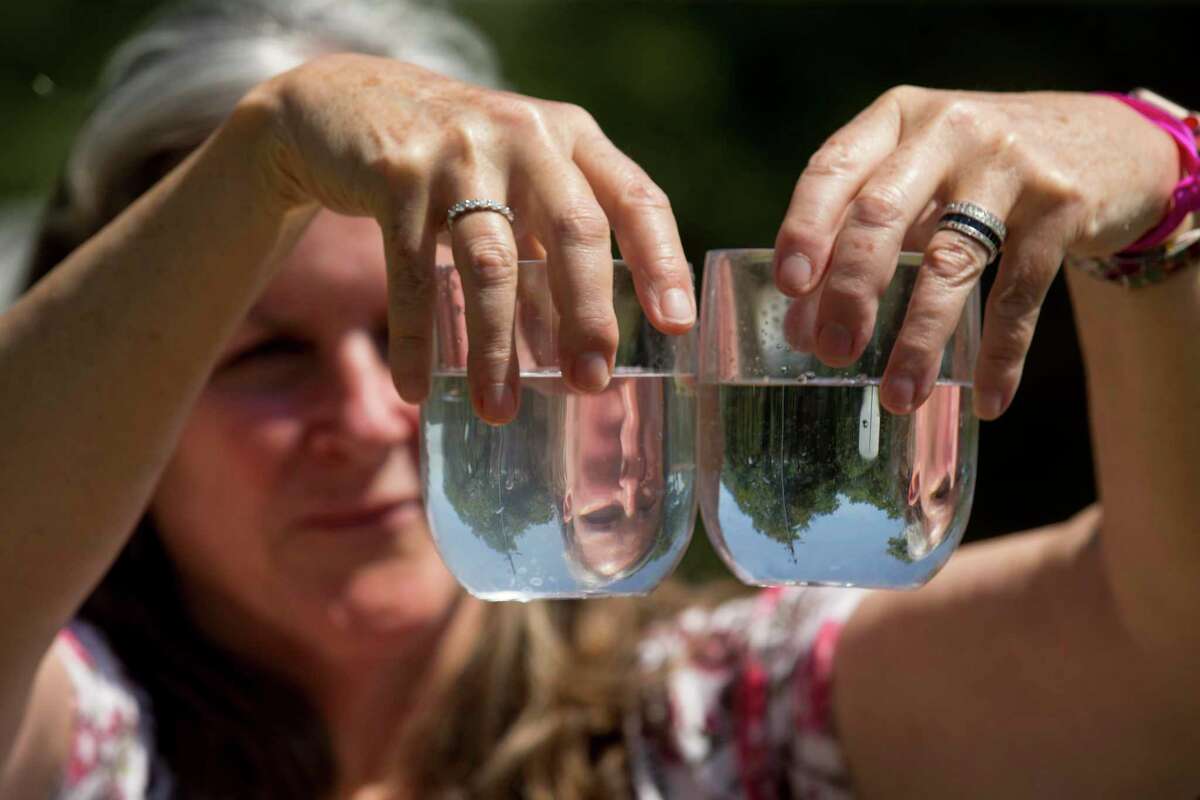 Dr. Teri Albright compares a water sample from her well, left, and compares it to a glass full of bottled water on Monday, May 11, 2020 in Blanco, Texas. After crews working for pipeline giant Kinder Morgan spilled drilling fluid during a boring operation near the Blanco River in late March, several homeowners say their wells were contaminated. Albright's well water has became contaminated.