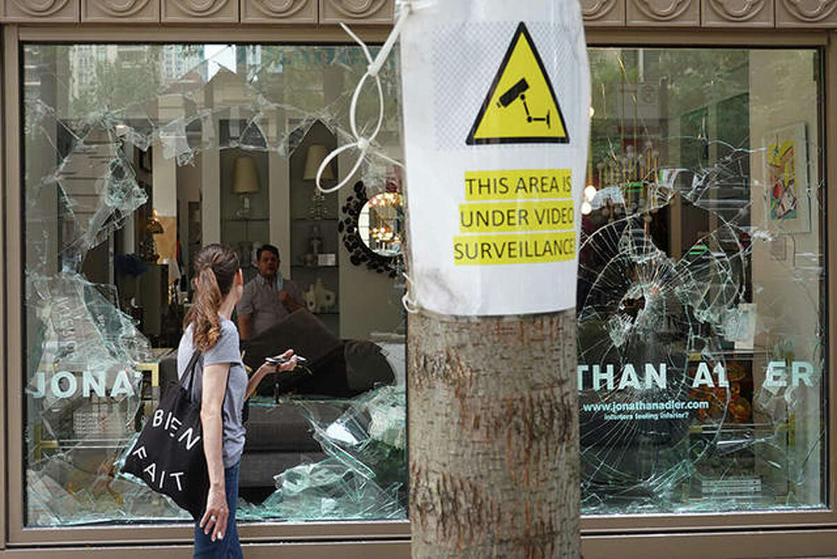 A woman looks through the shattered glass window of an interior design store that was looted in Chicago. Police made more than 100 arrests as widespread looting and disorderly conduct were reported downtown and other areas of the city. Officials believe the violence had apparently grown out of a shoot out between police and a suspect.