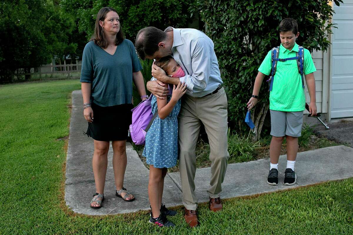 Kevin Thompson hugs his daughter, Elizabeth, 10, goodbye, next to her twin brother, Tucker, as their mother, Sarah Thompson, waits to walk them to Curington Elementary School for their first day of fourth grade in Boerne on Wednesday.