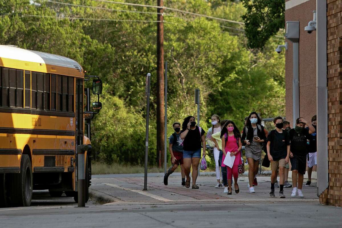 Students walk into Boerne Middle School North after exiting a bus on the first day of school in Boerne on Aug. 12. High percentages of students have returned to classrooms there. Some rural districts, worried about absenteeism, are canceling online learning options.