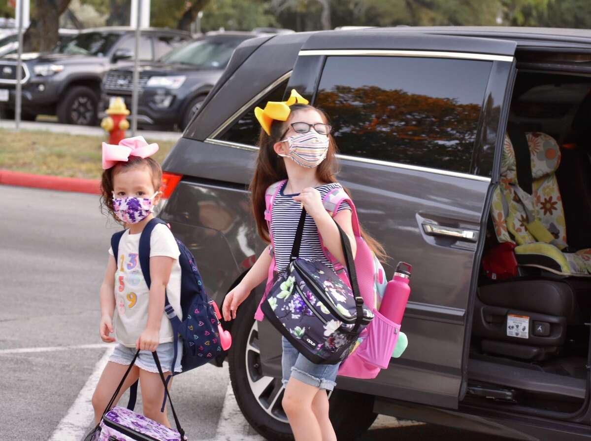 Two students walk into school with masks on their first day of class.