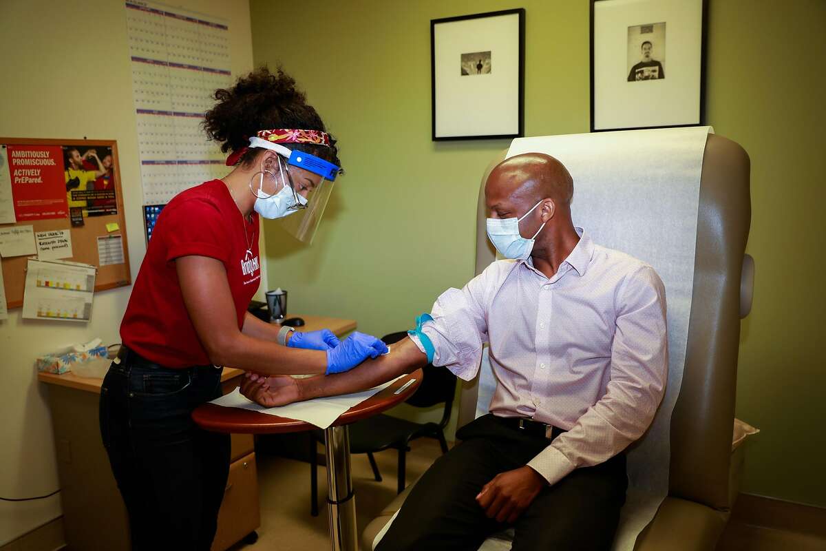 Lab coordinator Gabriella Green (left) draws Dr. Hyman Scott�s blood as a part of routine blood draw that are done at Bridge HIV on Wednesday, Aug. 12, 2020 in San Francisco, California.
