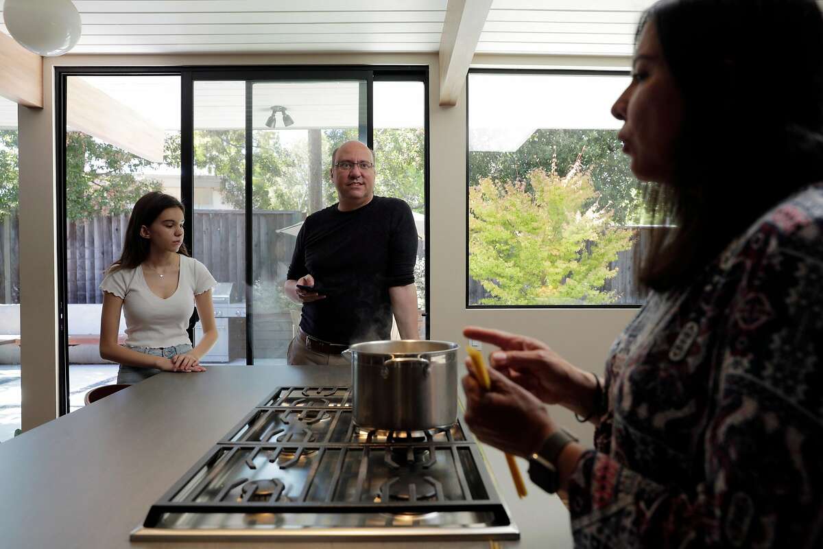 Connie Lares Ruspini, right, begins to prepare lunch for her family, at their home in Sunnyvale, Calif., on Wednesday, August 12, 2020. The entire family got sick with COVID-19 in the spring. Connie Lares Ruspini, a medical interpreter at Lucile Packard Children's Hospital Stanford, took leave from work on April 7 - her birthday - and spent the day going from room to room in her home, checking the temperatures and oxygen levels of her family members. Her 16-year-old daughter Natalia felt fatigued and her body ached. Her husband Diego was coughing, feverish, vomiting, and had diarrhea and had a weeklong hospital stay to receive oxygen. Twelve-year-old Santiago was asymptomatic - except for eating three times what he normally would. Ruspini was tired, had pain in her joints, ran a mild fever, and lost her appetite.