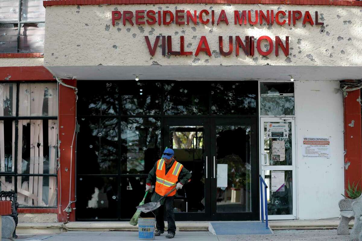 A worker cleans up outside the bullet-riddled Municipal Presidency of Villa Union, Monday, Dec. 2, 2019. The small town near the U.S.-Mexico border began cleaning up even as fear persisted after a weekend gunbattle between a heavily armed drug cartel assault group and security forces.