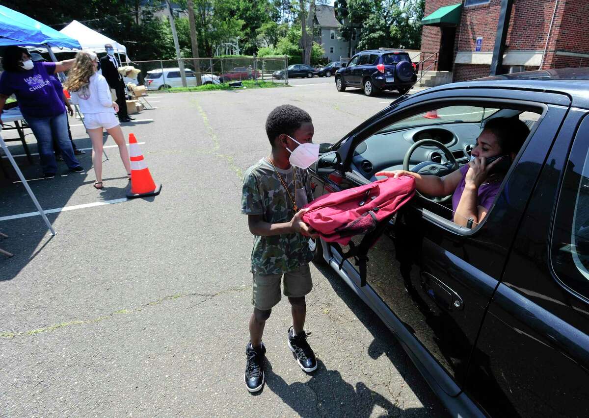 Robert Jackson Jr., 8, of Bridgeport helps distribute new backpacks to families during a Back-to-School event hosted at the Bethel AME Church on Saturday.