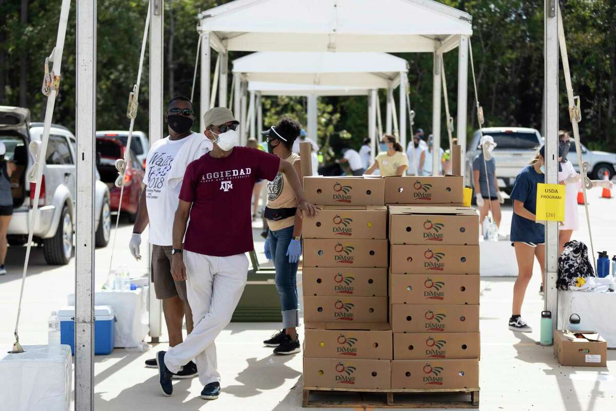 Furthest left, Charles Hayes and Mohammad Tayyab wait for vehicles to pull up during a food distribution event at Planet Ford Stadium in Spring, Tuesday, August 11, 2020. Northwest Assistance Ministries partnered with the Houston Food Bank and Spring ISD to host a Neighborhood Super Site Food Giveaway to assist families facing food insecurity.