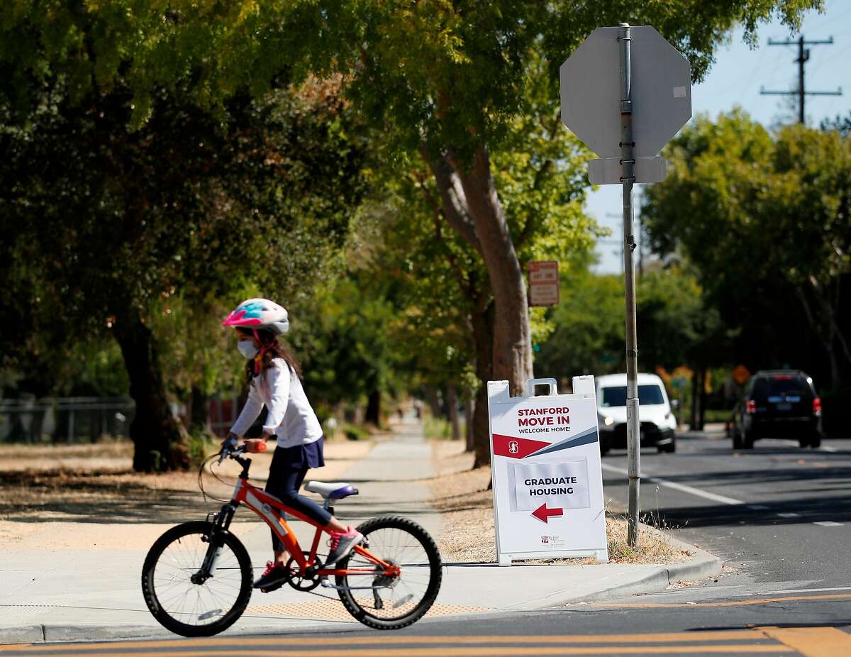 Bicyclist rides pass the Stanford graduate housing move-in sign on display near Stanford University, California, on Friday, August 7, 2020.
