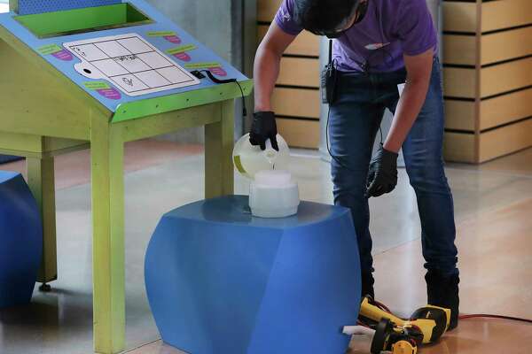 Walter Fica refills a sprayer with disinfectant as he and other staff members at the DoSeum perform a thorough burst cleansing of the entire children's museum between blocks of visitors.