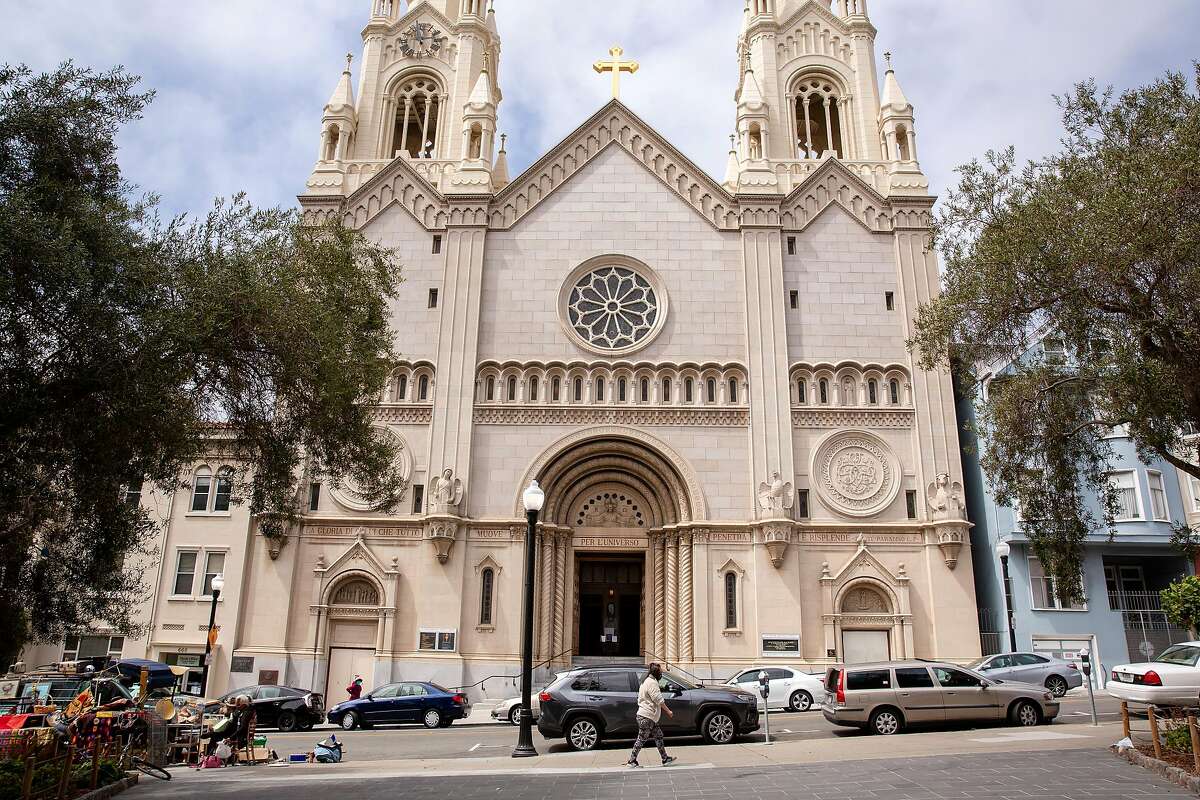 People walk past the open doors of the Saints Peter and Paul Church in San Francisco, Calif. on Friday, July 24, 2020.