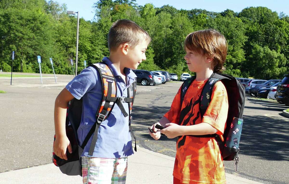 T.J. Hahn, 6, greeted his pal Max Frattaroli, 5, in front of East School in New Canaan on a recent first day of school in the town. Moments before they had hugged each other hello. Sharing will be discouraged when the town’s public schools re-open in the fall amid the coronavirus pandemic.