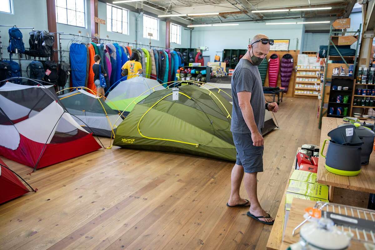 John Mitchell looks for bear-proof equipment at Sports Basement on Thursday, Aug. 13, 2020, in Berkeley, Calif. There’s a jolt in sales for camping equipment, as people want to leave their house during the coronavirus pandemic. Mitchell is preparing for a camping trip for the weekend at Cole Creek Lakes. He said he had a hard time finding the gear he needed after shopping at multiple locations.