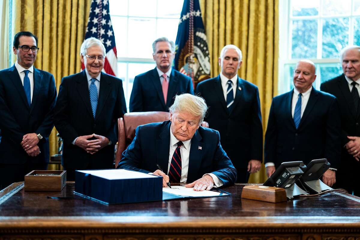 U.S. President Donald Trump signs H.R. 748, the CARES Act in the Oval Office of the White House on March 27, 2020 in Washington, D.C. Earlier on Friday, the U.S. House of Representatives approved the $2 trillion stimulus bill that lawmakers hope will battle the the economic effects of the COVID-19 pandemic. (Erin Schaff/Pool/Getty Images/TNS)