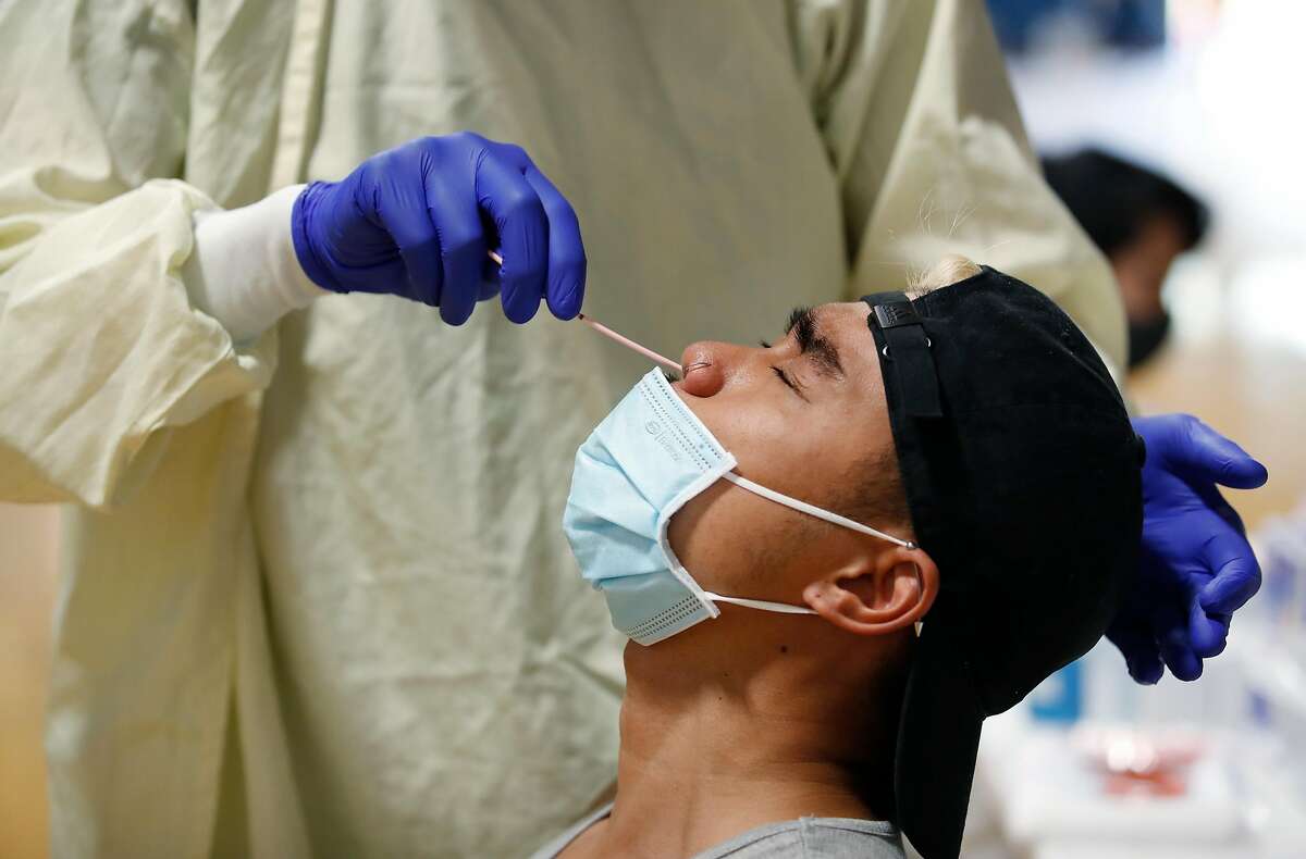 Nurse Anna Tan, of Santa Clara County, collects a sample from Julius Caesar Melanio during COVID-19 pop-up testing at William C. Overfelt High School in San Jose, California, on Thursday, August 13, 2020.