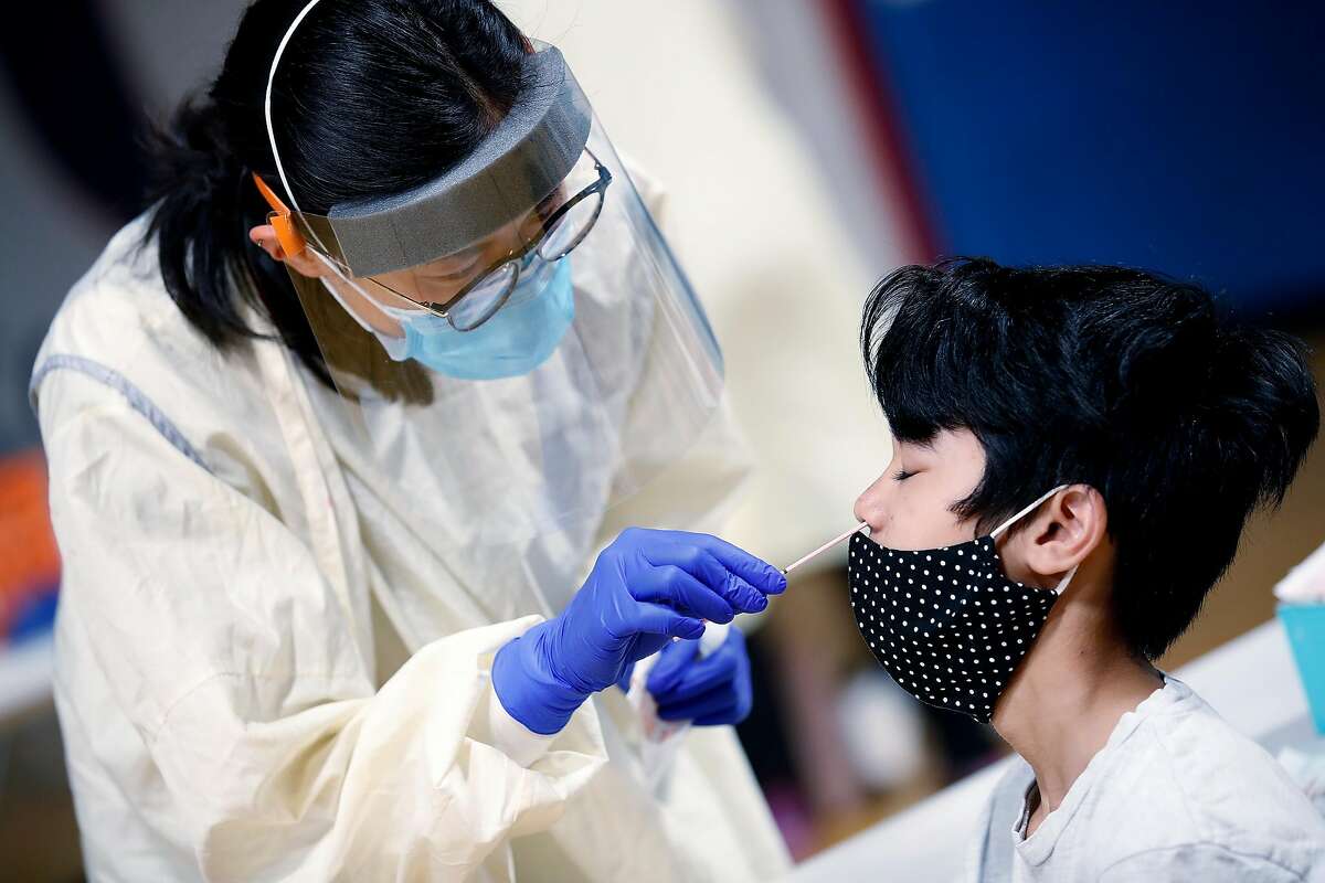Nurse Anna Tan, of Santa Clara County, collects a sample from Moses Melanio during COVID-19 pop-up testing site at William C. Overfelt High School in San Jose, California, on Thursday, August 13, 2020.